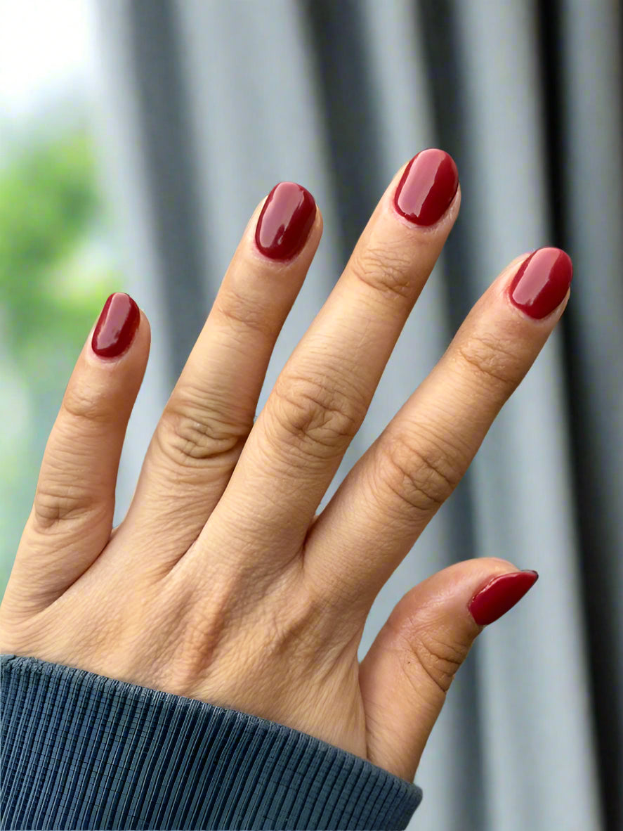 Glossy wine red dip powder manicure on natural nails