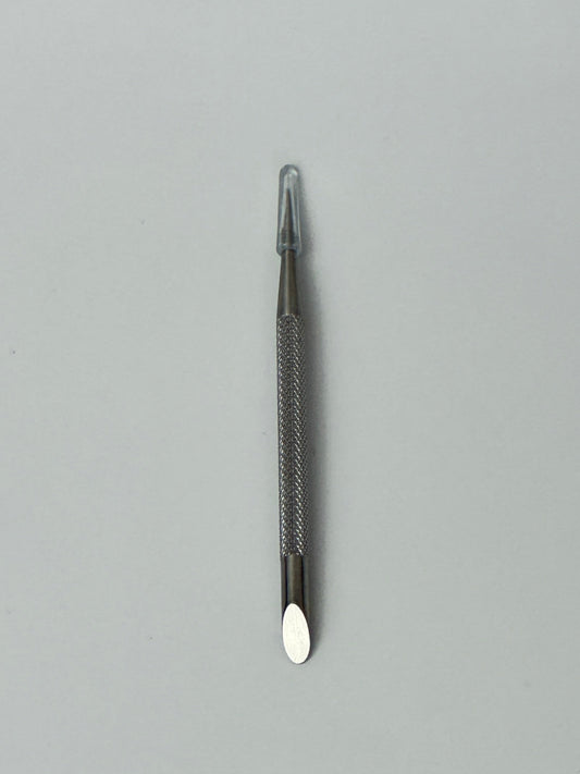 Stainless steel dual-ended cuticle pusher placed on a plain background, used for pushing back cuticles and cleaning around the nail